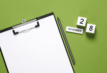 Business concept, planning, deadline. Block Calendar with date november 28 and clipboard on green background.