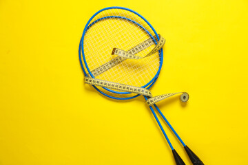 Batbinton rackets wrapped with measuring tape on a yellow background