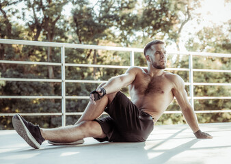 Obraz premium Muscular man with naked torso practicing stretching outdoors