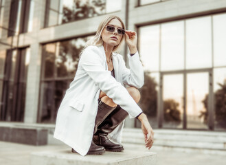 Young fashion blonde woman in trendy outfit posing in the city. Street fashion