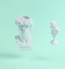 Levitating Antique Plaster busts of David and Venus on blue background with shadow. Conceptual pop....