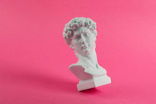 Antique Plaster David bust on pink background. Conceptual pop. Minimal still life photography