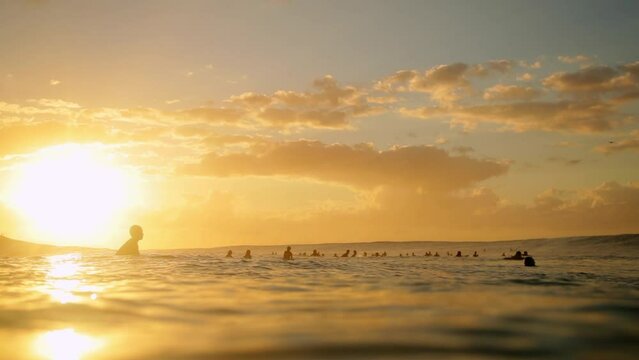 Slow Motion Shot Of People Swimming With Surfboards In Ocean Under Clouds During Sunset - Oahu, Hawaii