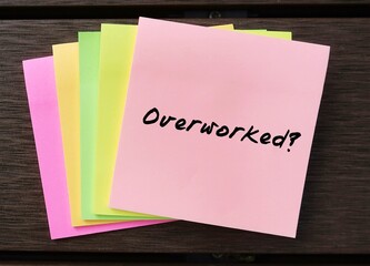 Office note pad with handwritten text OVERWORKED, concept of professional life leaving one feeling...