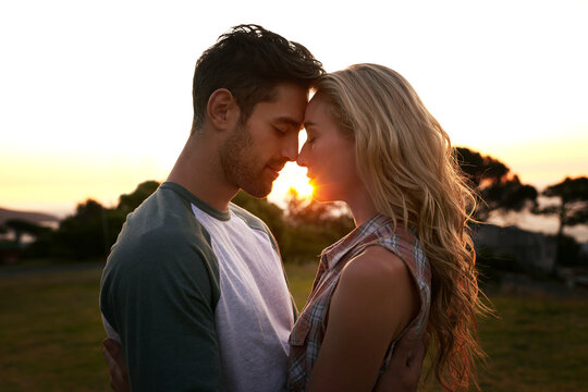 Sunset, love or couple in nature on romantic holiday vacation for bonding or relaxing on date together. Forehead, travel or people hug or embrace in summer with romance or peace in park in the dark