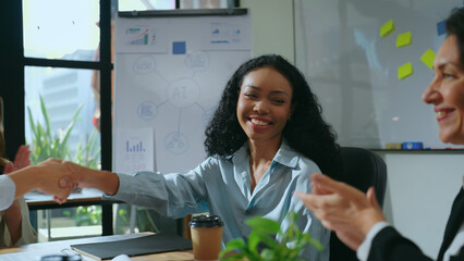 The beautiful businesswoman shaking hands with her team at meeting room, signifying her agreement...