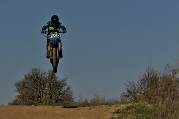 Kyiv, Ukraine - Jump on a motorcycle against the blue sky during a workout. Active extreme rest. A motorcycle racer flies over a hill.