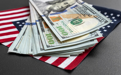 Dollar bills with small american flags on black background.