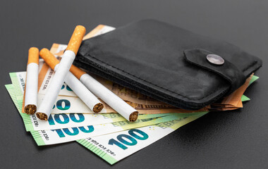 Cigarettes with wallet and euro bills on black background.