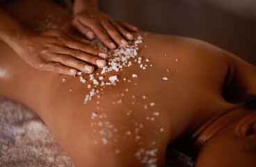 Salt, spa scrub and beauty therapist hands with woman customer at a hotel with massage. Exfoliate therapy, luxury and relax treatment of a female person back for skincare and wellness exfoliation