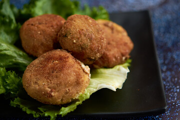 Breaded potato nuget, with orejona lettuce, with dry chile sauce, a coffee in the background
