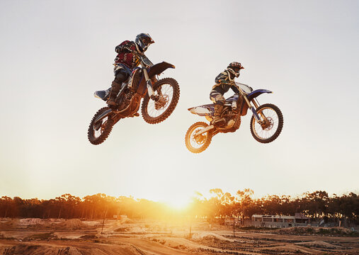 Motorbike, jump and adventure during race for competition as transportation with sunset. Men, motorcycle and action for sports in the outdoor on fast course with power and moving fast with risk.