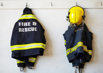 Firefighter, uniform and clothing hanging on wall rack at station for fire fighting protection....