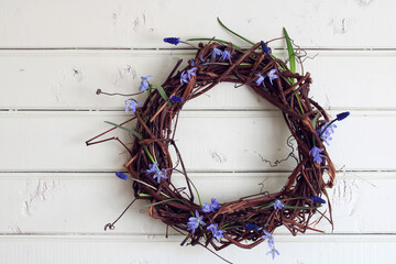 A wreath of branches of grapes and the spring flowers on a wooden background.