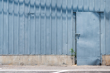 Warehouse building with a blue doorway and metal sheet wall. Indsutrial building background object photo.