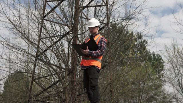 An electrical engineer inspects the power line and records the data of electrical sensors in a log. Energy crisis in the country.