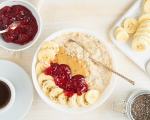 Top view of oatmeal porridge with strawberry jam, peanut butter