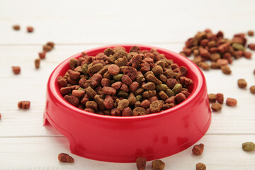 Pet food in red bowl on white background.