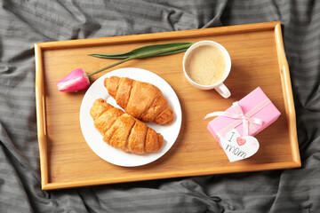 Happy mother's day, beautiful breakfast on tray, lunch with cup of coffee, fresh croissants, tulip and gift. Spring holiday, family relations.