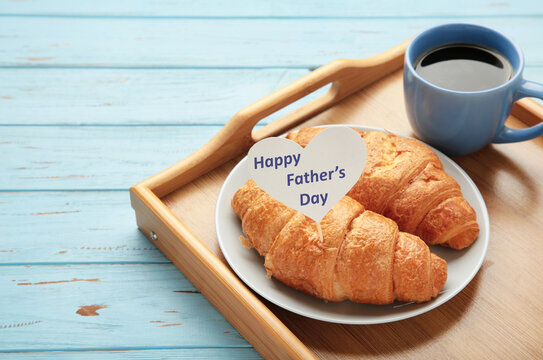 Father's day concept with gift, card and breakfast. Breakfast for dad with croissant and coffee.