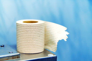 Poor quality toilet paper on a metal toilet tank in a public toilet