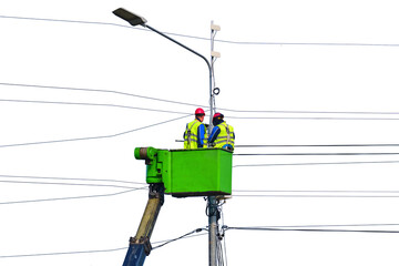 Electrical engineers repair the line standing on the crane platform at a high pole, isolated on a white background