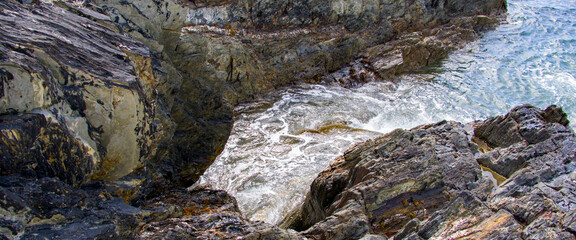 Coastal rocks and sea water on a sunny day. Landscape, rock formation on sea.