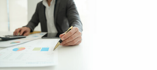 businessman or accountant working on calculator and laptop computer to calculate business data during using accountancy document at office.