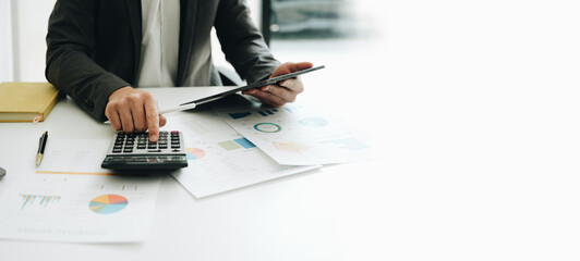 Young asian male work with financial papers at home count on calculator before paying taxes...