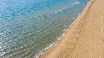 Aerial view of a coast of the Mediterranean sea near Sabaudia, in Italy. The beach is empty and sandy. Nobody is swimming.