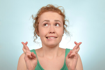 A woman with red hair top crosses her fingers.