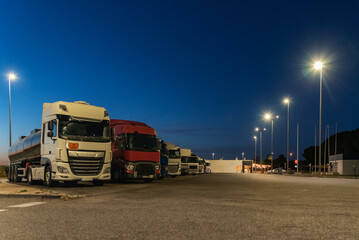Fototapeta na wymiar Trucks resting in a highway service area at night, mandatory daily rest.