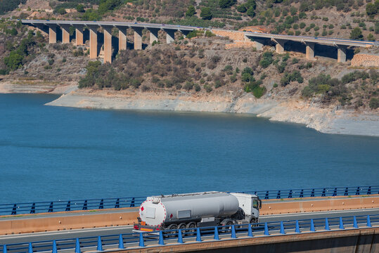 Tanker truck for the transport of fuels circulating on a bridge, in the background several more viaducts.