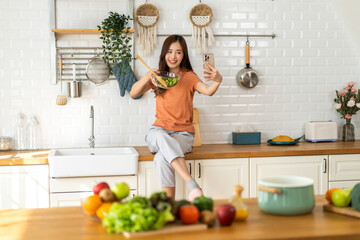 Portrait of beauty body slim healthy asian woman having fun cooking and preparing cooking vegan food healthy eat with fresh vegetable salad on counter in kitchen at home.Diet concept.Fitness, healthy