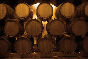 oak wooden Wine barrels in a old, dark wine cellar. front view. Cognac store basement of wooden brandy, beer. Wine storage vault. row of stacks of whisky barrels, set down to mature, in warehouse.