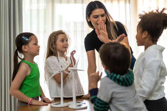 Portrait happy teacher help school children student having fun activity learn play renewable energy from solar windmill, education, science, environment, Eco, wind turbines, class at elementary school