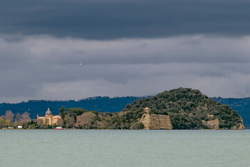 Fototapeta na wymiar The Bisentina island of Lake Bolsena seen from Capodimonte, Italy, under a stormy sky
