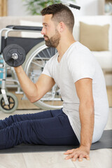 young handsome disabled man with barbell and dumbbells