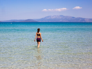 Fototapeta na wymiar Girl in a swimsuit standing in the sea on a sunny day, healthy lifestyle, travel, sport concept 