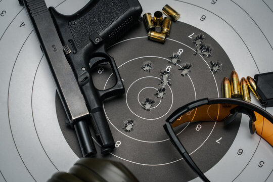 Shooting from a pistol in a shooting range.  9mm pistol target with bullet holes in the center, goggles and earmuffs, close-up photo.
