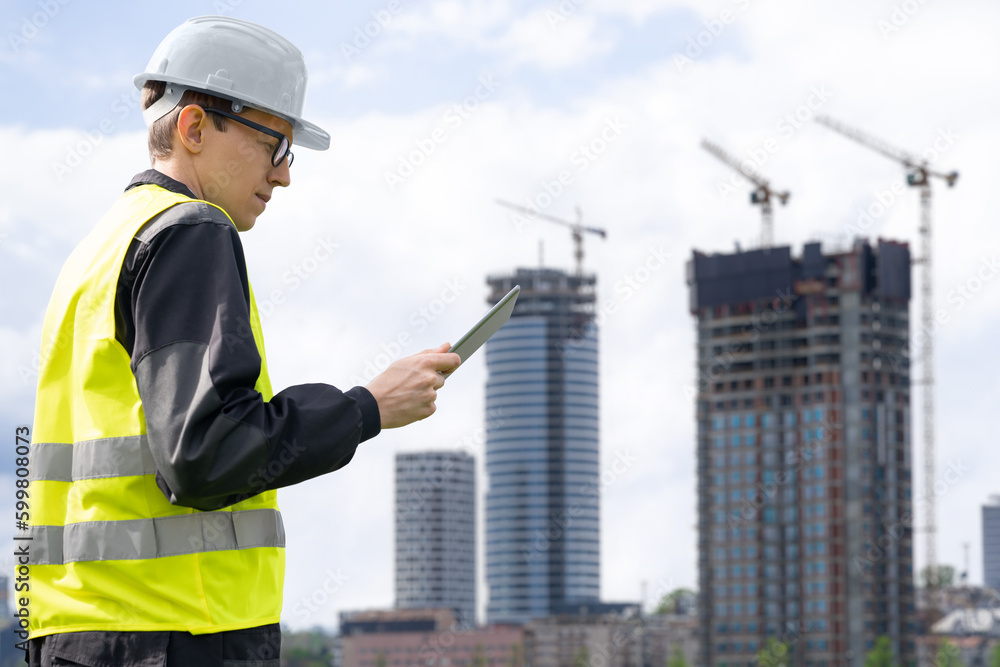 Aufkleber Engineer with a digital tablet on the background of a building under construction	