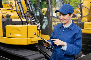 Woman with digital tablet on the background of construction machines	