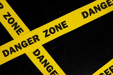 Danger zone caution and warning concept. Yellow barricade tape with word in dark black background.