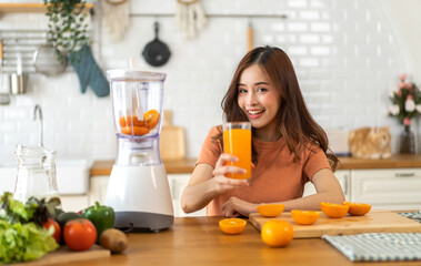 Portrait of beauty body slim healthy asian woman drinking glass of juice and orange.young girl preparing cooking healthy drink with fresh orange juice in kitchen at home.Diet concept.healthy drink