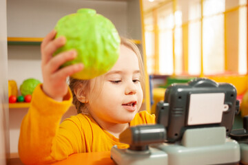 child in kindergarten, playroom, playing with toys, learning. Plays in store, vegetables and...
