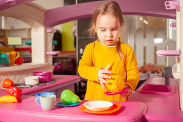 child in kindergarten, playroom, playing with toys, learning. plays in kitchen, cooks vegetables and fruits