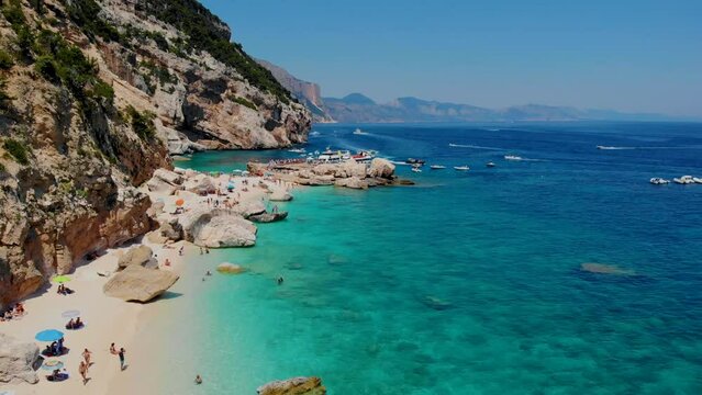 people on the sandy beach and blue sky called Cala Mariolu beach, near Cala Biriola and Cala Goloritze, Baunei, Sardinia, Italy during summer