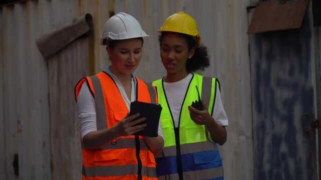 group of two diversity woman container worker working together with tablet computer  in  warehouse logistic in Cargo . cooperation of african american woman and Caucasian female.