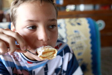 Child eating pancakes stuffed with cottage cheese