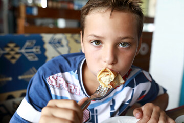 Boy eating pancakes stuffed with cottage cheese